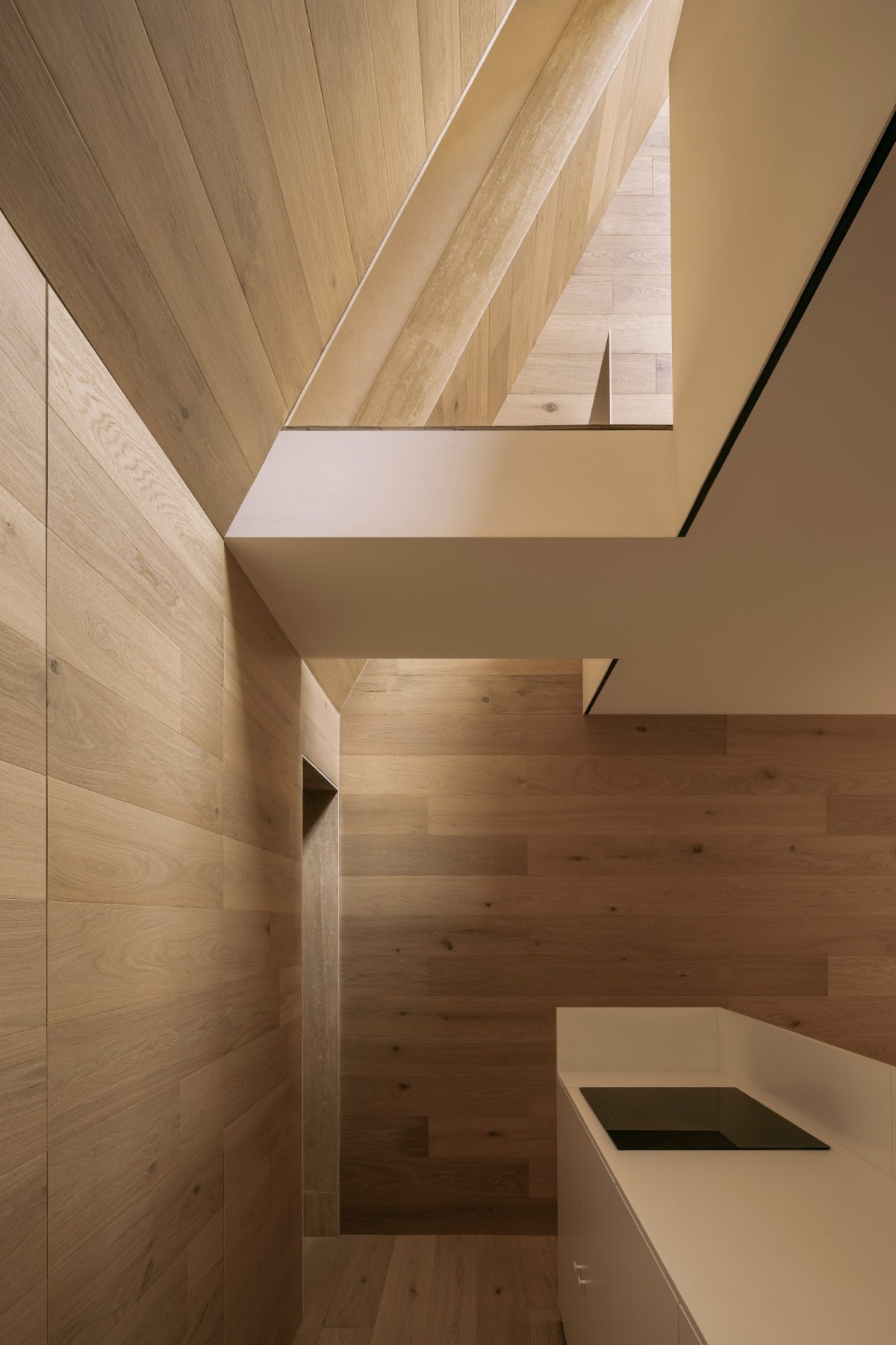 Una cocina discreta y parcialmente iluminada se funde con la sala de estar y da acceso a la escalera de caracol.