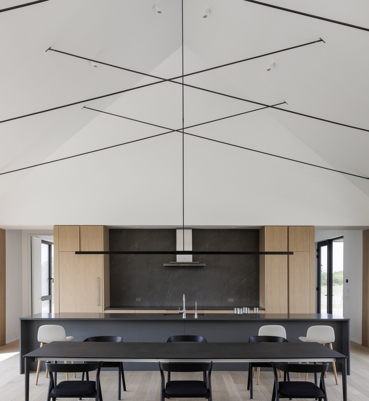 En el lado opuesto, la cocina combina tonos oscuros que dialogan con la chimenea, creando una coherencia visual sin renunciar al contraste.