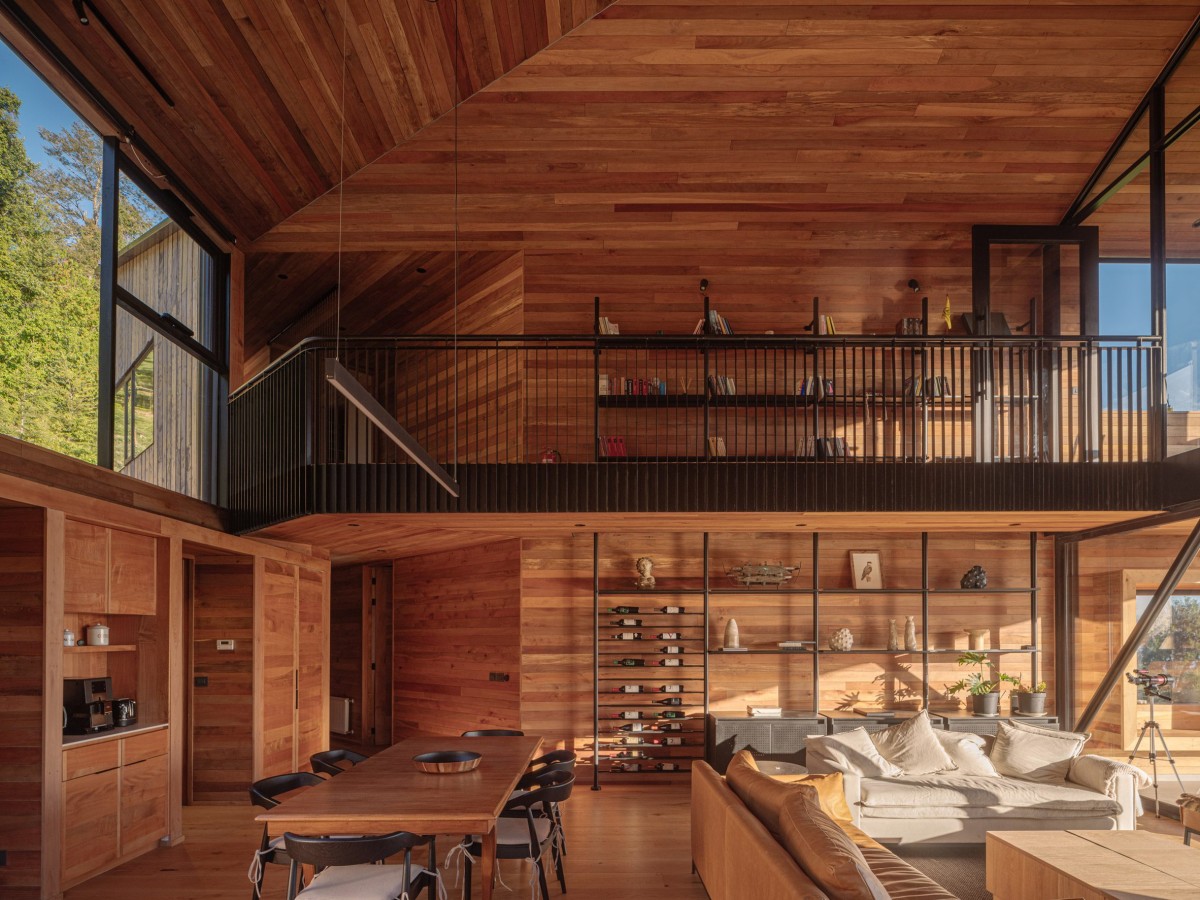 Al entrepiso se accede por un puente interior con barandilla metálica negra que discurre junto a una estantería metálica prefabricada.