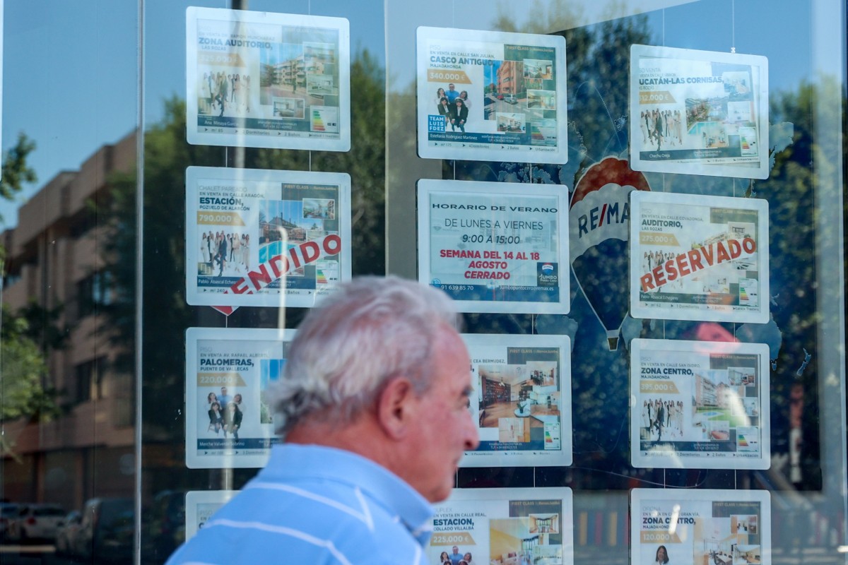La compraventa de viviendas cae un 2% en mayo, hasta las 62.587 unidades, según los notarios Un hombre camina frente a un escaparate de anuncios de viviendas, en Madrid (España)
