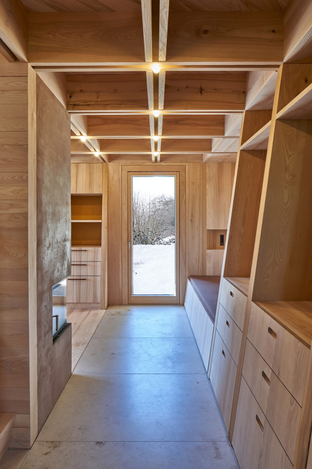 Un pequeño vestíbulo entre grandes vigas de madera que actúa como filtro hacia el comedor, la cocina y un baño compacto.
