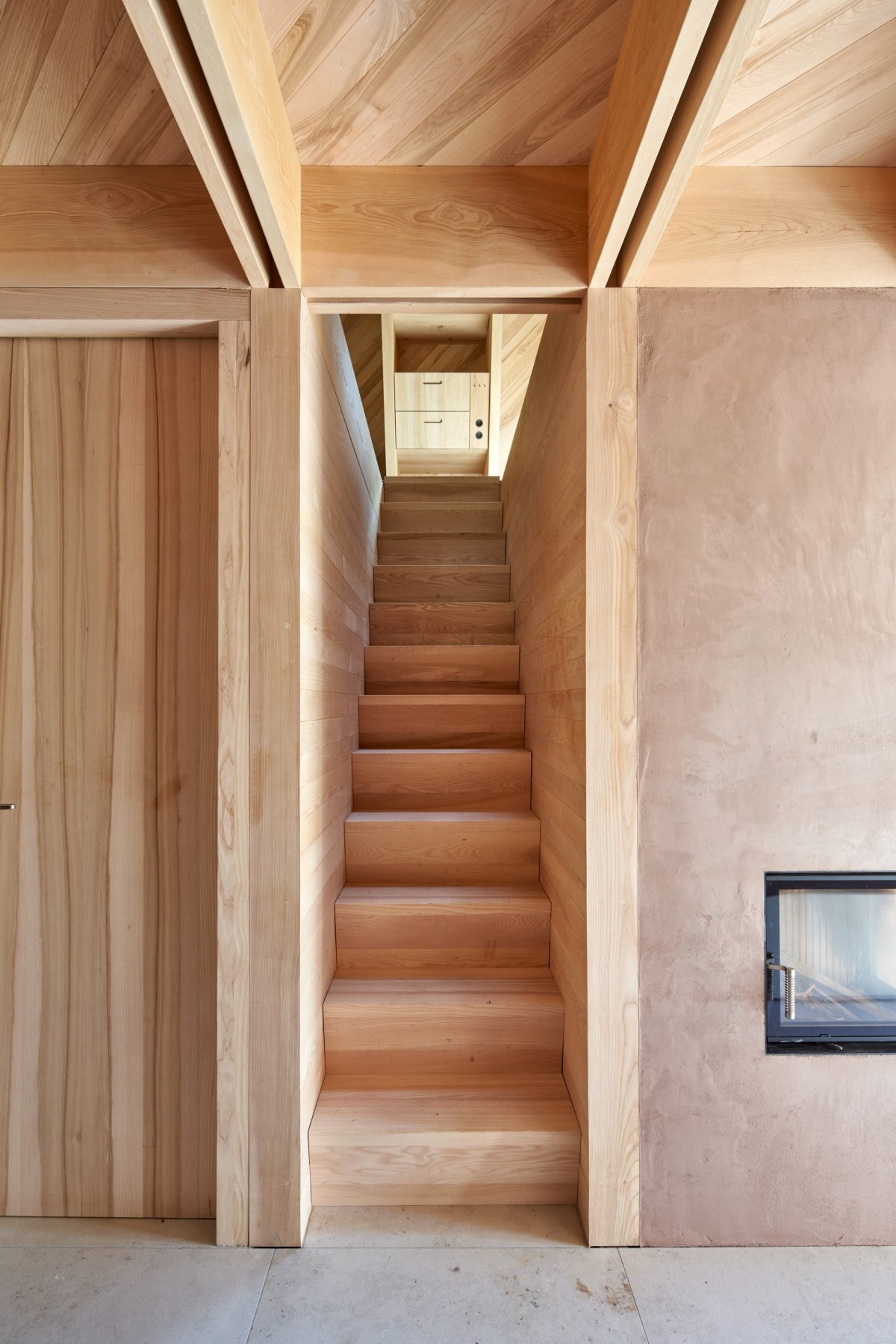 La escalera, de un solo tramo, conduce a una planta superior diáfana que sirve al mismo tiempo como dormitorio, sala de estar y despacho.