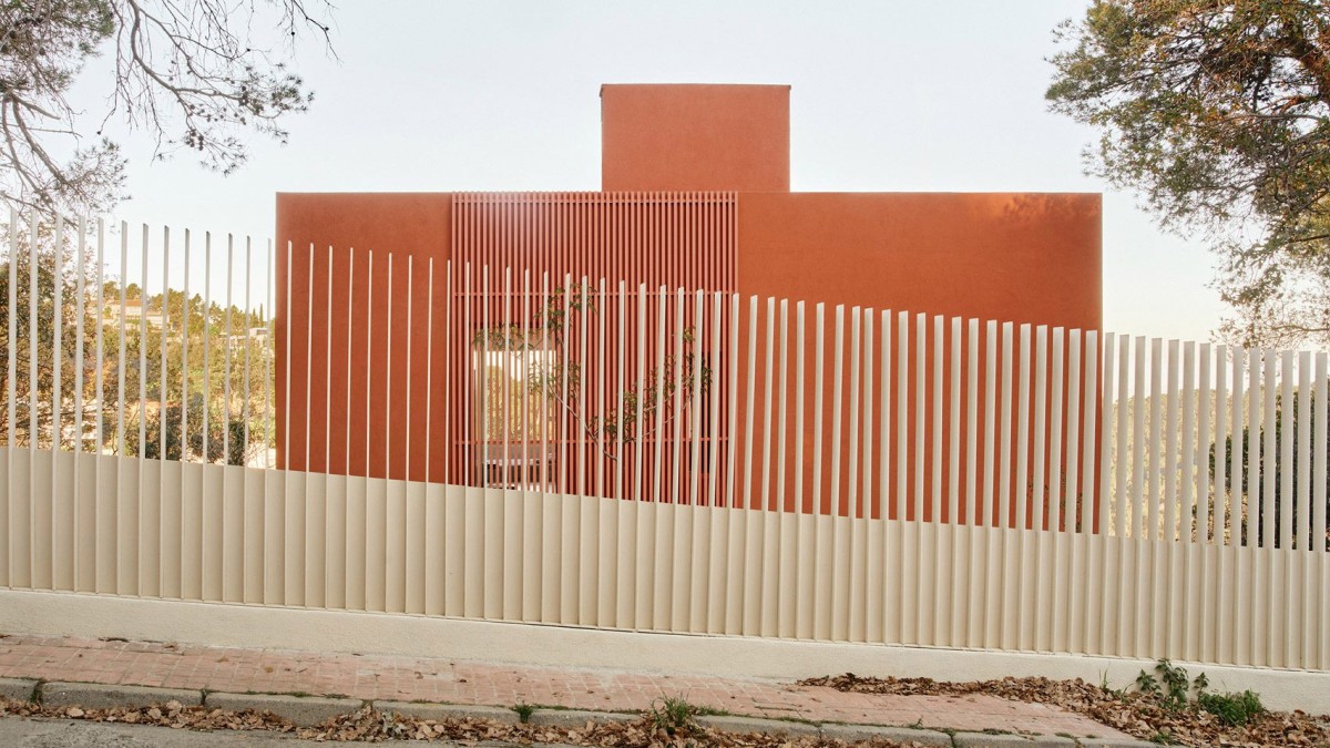La fachada está orientada a la carretera, protegida a su vez por una valla metálica y con una apariencia casi ciega.