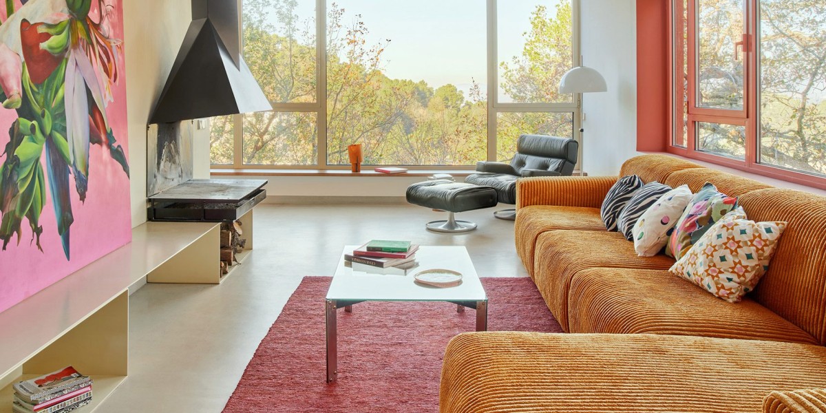 El salón se articula en torno a una chimenea angular de acero negro, que aporta un punto de contraste al predominio del hormigón y el vidrio.