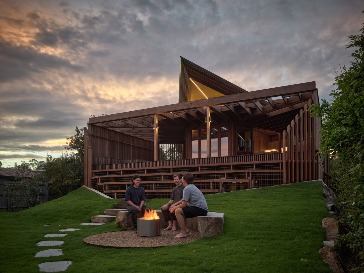 Unas sólidas gradas descienden hacia un jardín con zona de hoguera, fomentando la vida al aire libre.