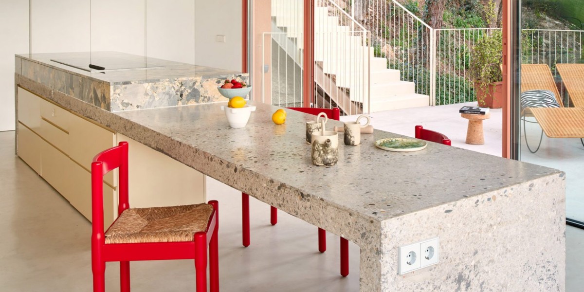 La cocina se organiza alrededor de una isla central de hormigón moldeado y ceppo di gré y tiene acceso directo a la terraza.