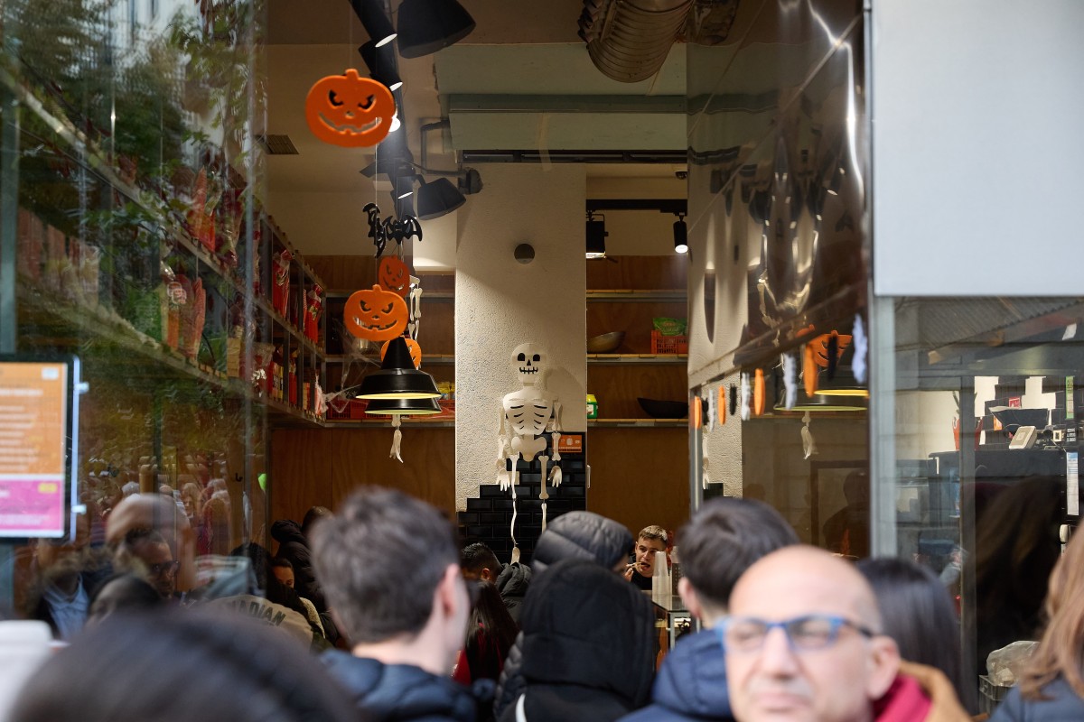 Archivo - Varias personas observan el interior de una tienda en Madrid por Halloween