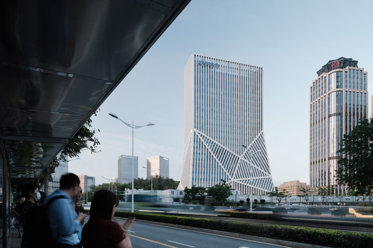 El edificio combina una monumental base con forma de montaña y una torre revestida con franjas de cerámica blanca.
