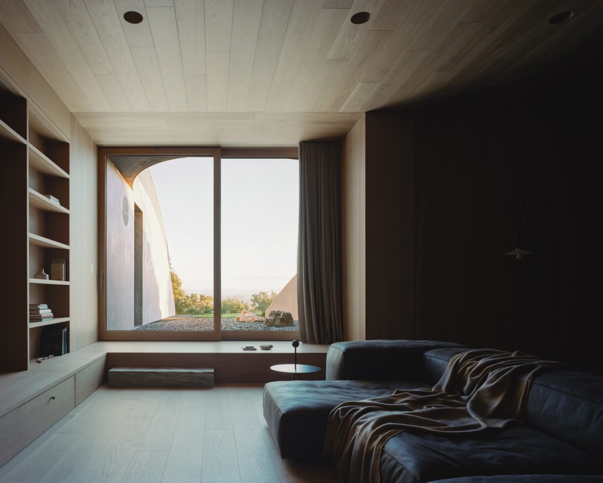 En la planta baja, los espacios, más recogidos por su revestimiento en madera cálida, se abren a patios de grava parcialmente cerrados. 