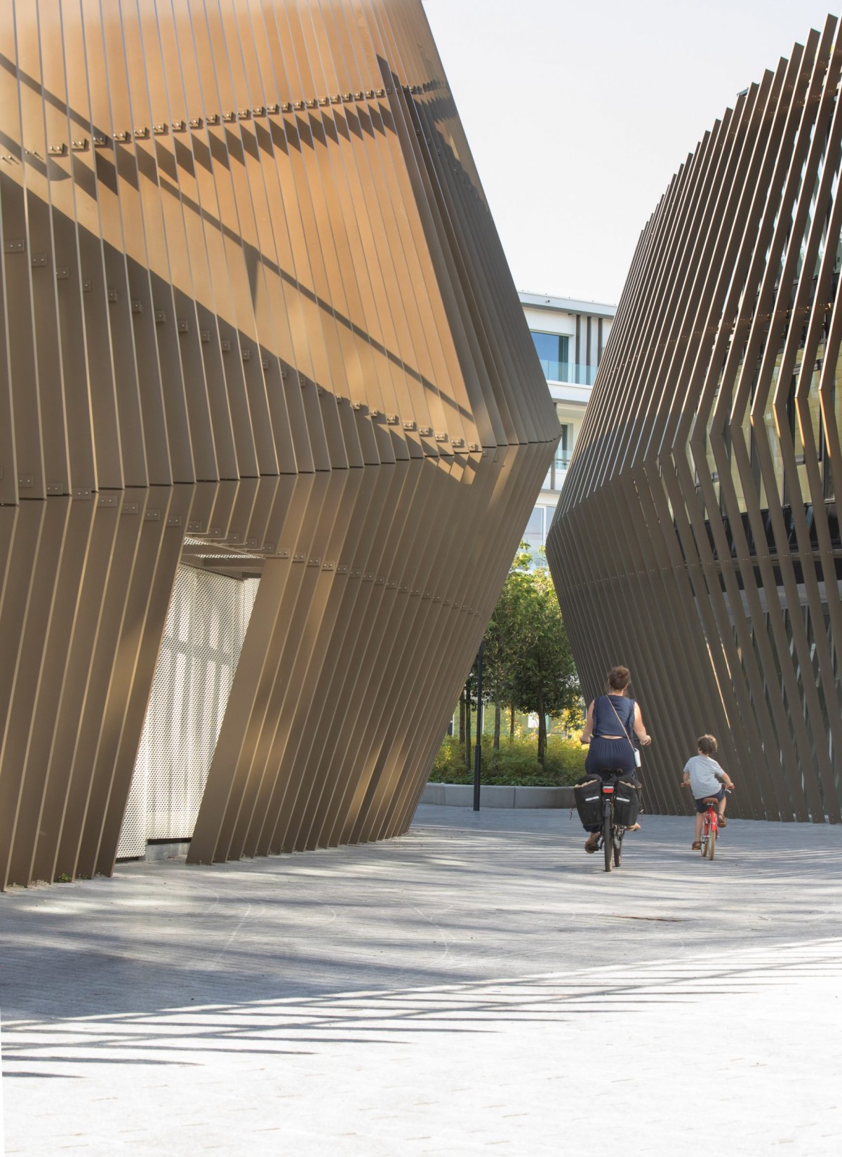 Los tres volúmenes se disponen en torno a una pasarela central arbolada, un corredor peatonal que conecta la estación con los barrios vecinos