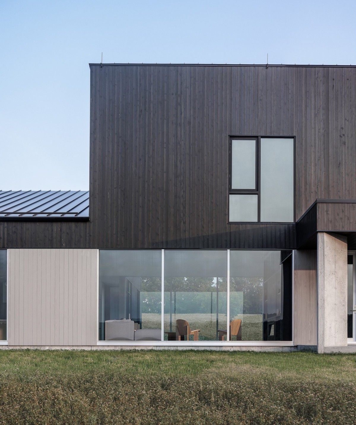 El exterior combina madera carbonizada y paneles de metal oscuro que evocan las construcciones agrícolas desgastadas por el tiempo.