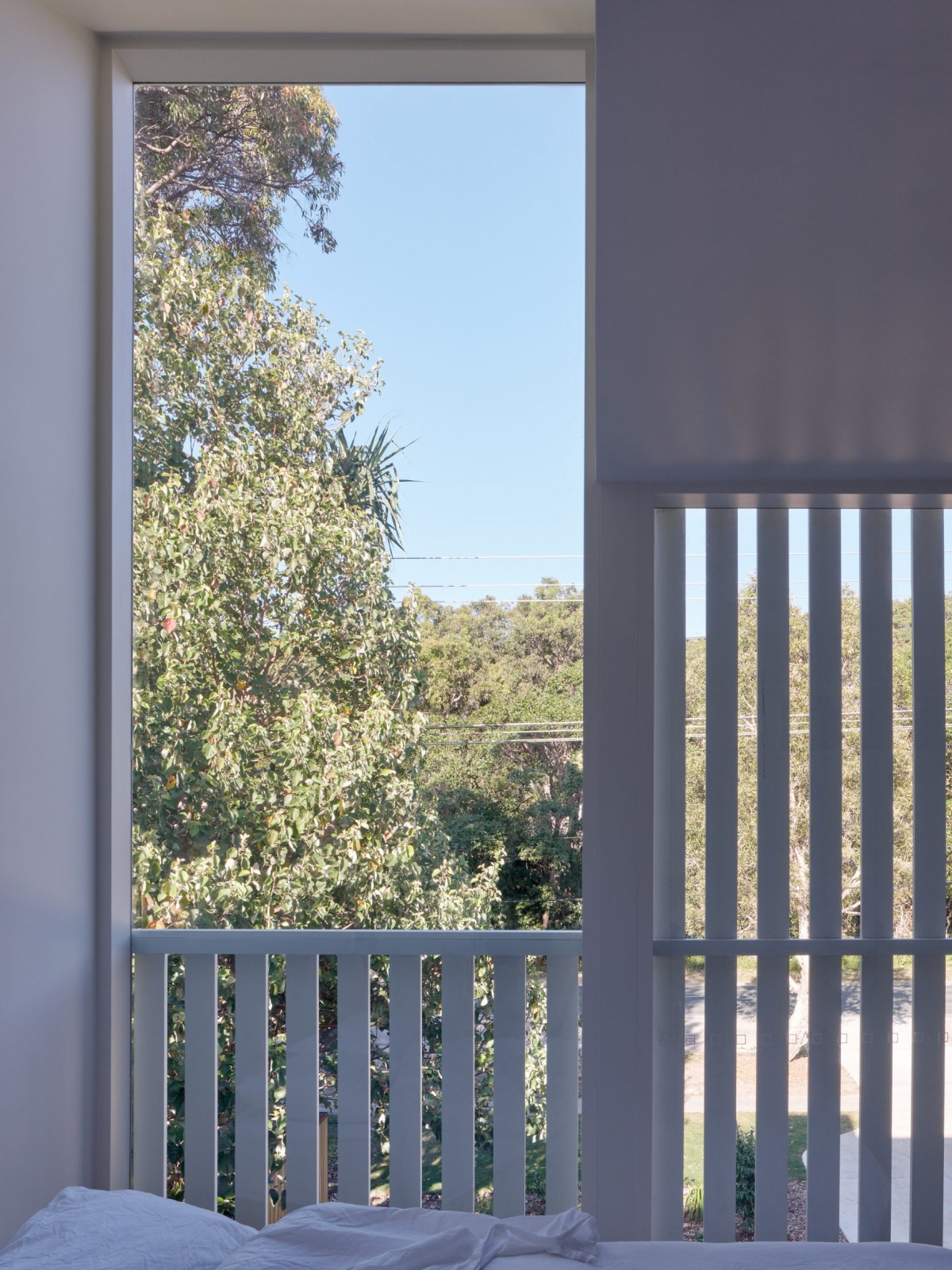 Las fachadas delanteras, donde están los dormitorios, se resuelven con ventanas altas y pantallas de tablones de madera pintados de blanco.