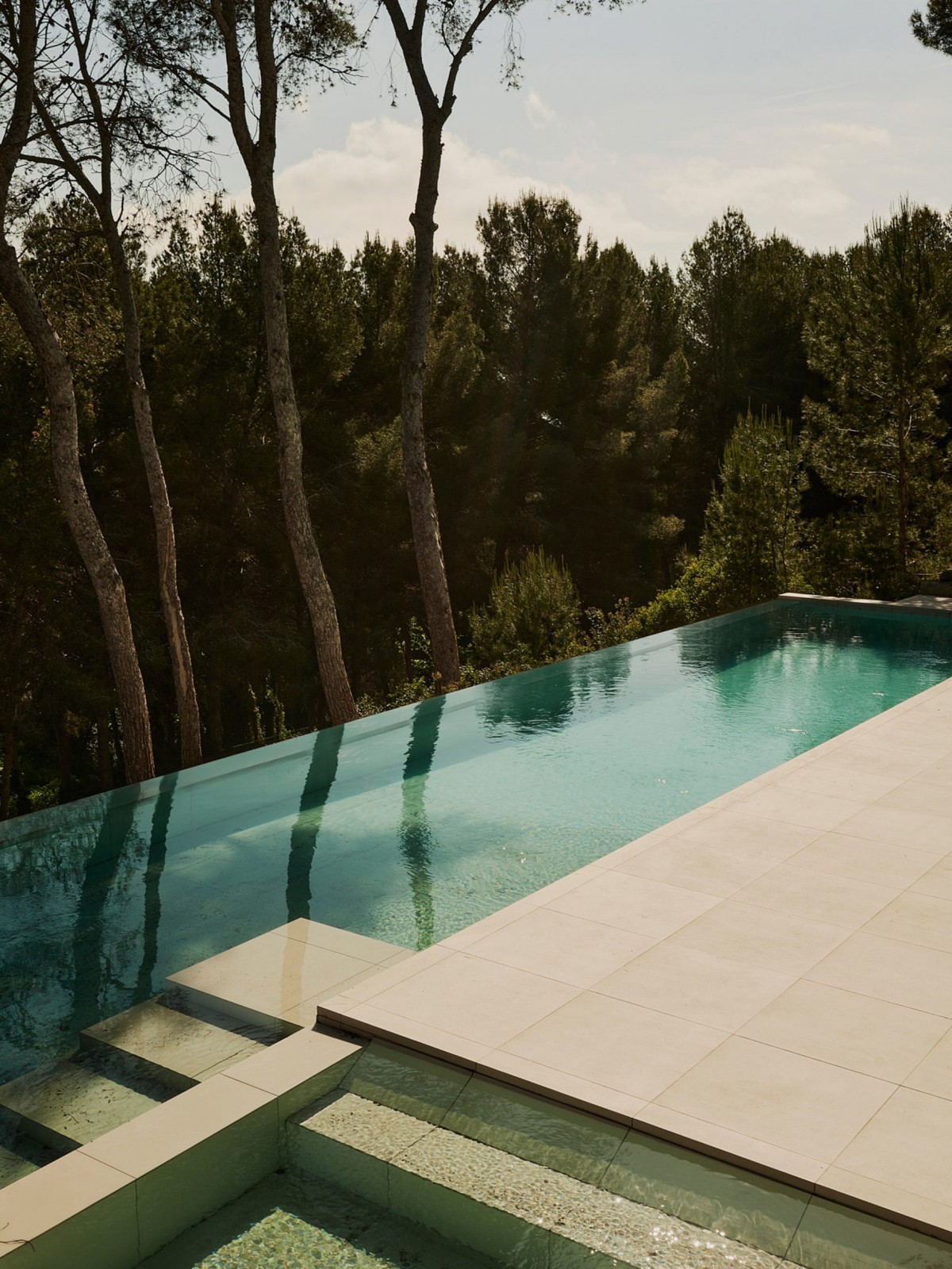 At the bottom of the house there is a swimming pool that acts as a transition to the garden, which slopes gently down to a densely wooded ravine.