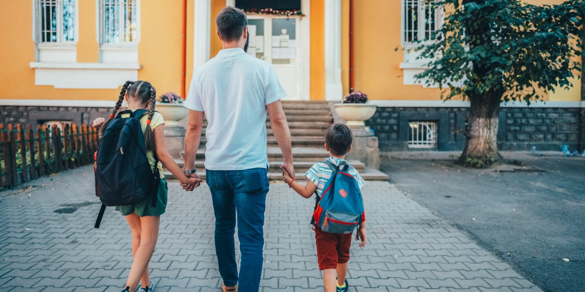 Un padre llevando a sus hijos al colegio