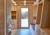 Un pequeño vestíbulo entre grandes vigas de madera que actúa como filtro hacia el comedor, la cocina y un baño compacto. 