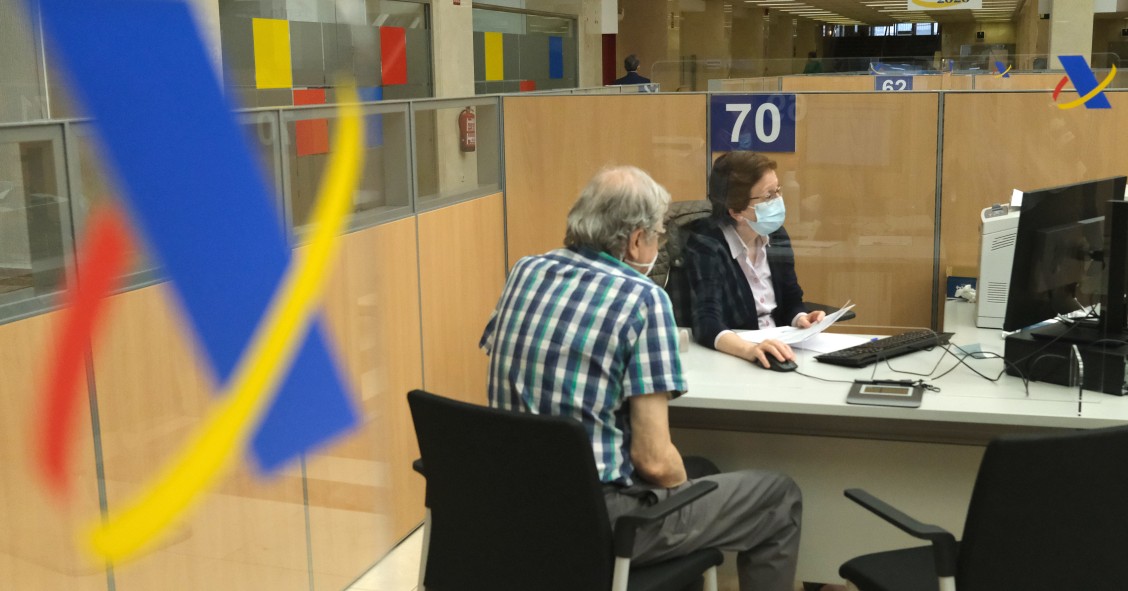Una empleada atiende a una persona de manera presencial desde una oficina de la Agencia Tributaria