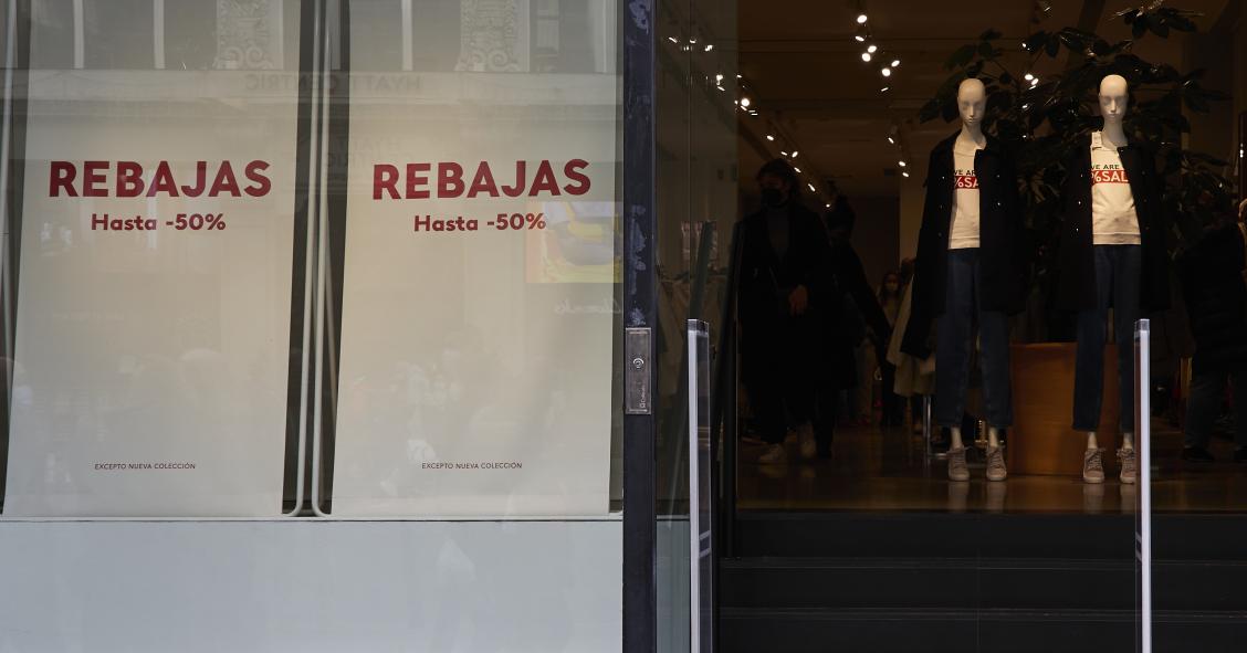 Entrada de una tienda de ropa con carteles de rebajas en una calle comercial del centro de Madrid