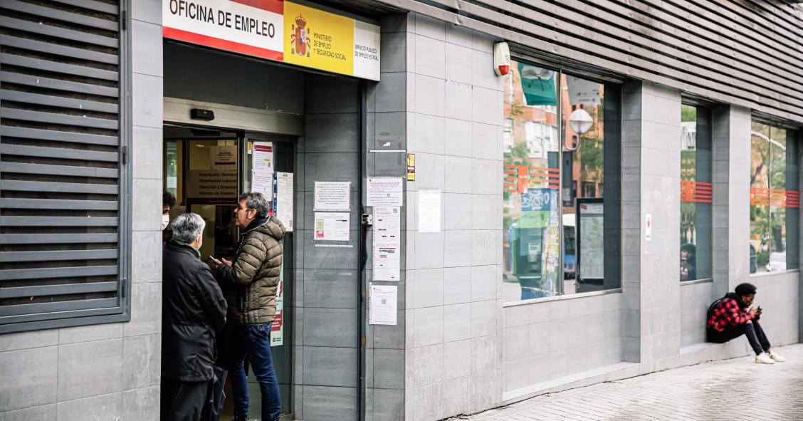 Varias personas en la entrada de una oficina de empleo 