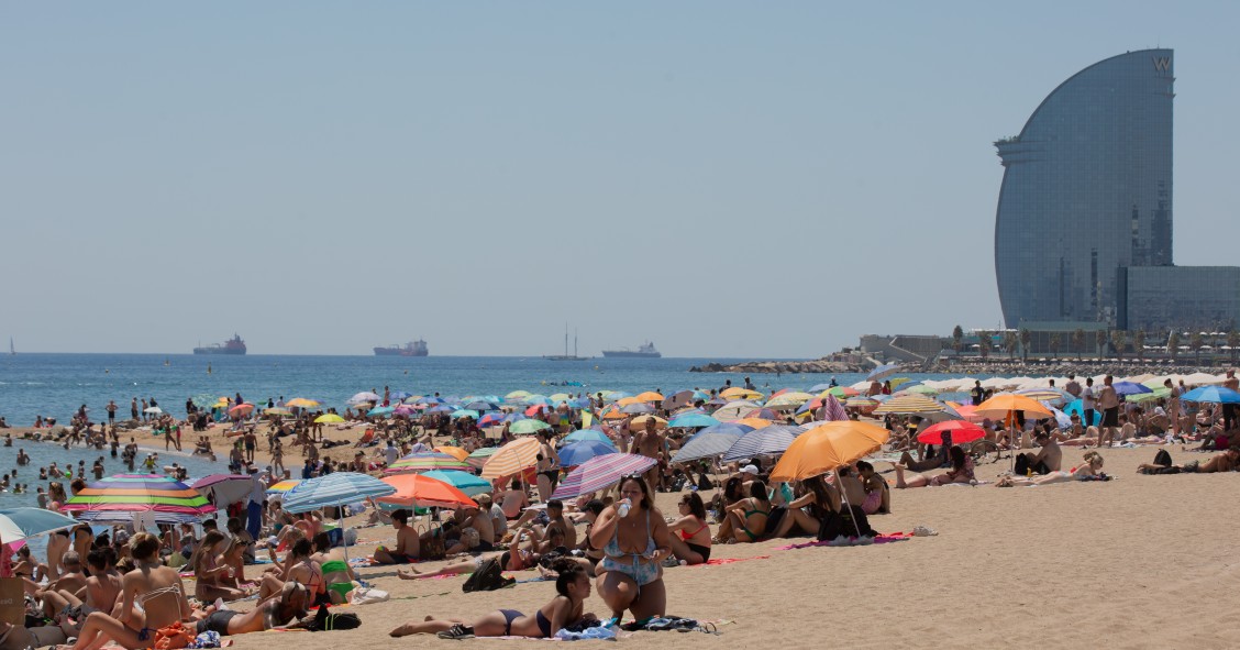 Varias personas se protegen del sol en la playa de la Barceloneta, en una imagen de archivo.