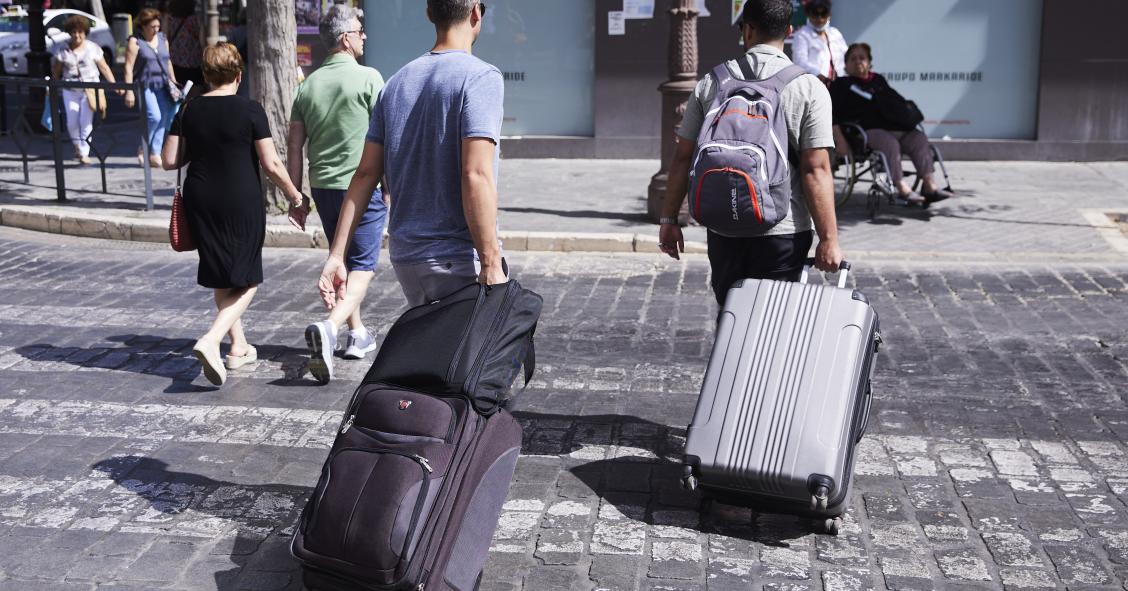  Dos turistas, con maletas, cruzan un paso de peatones a 21 de junio de 2022 en Sevilla (Andalucía, España)