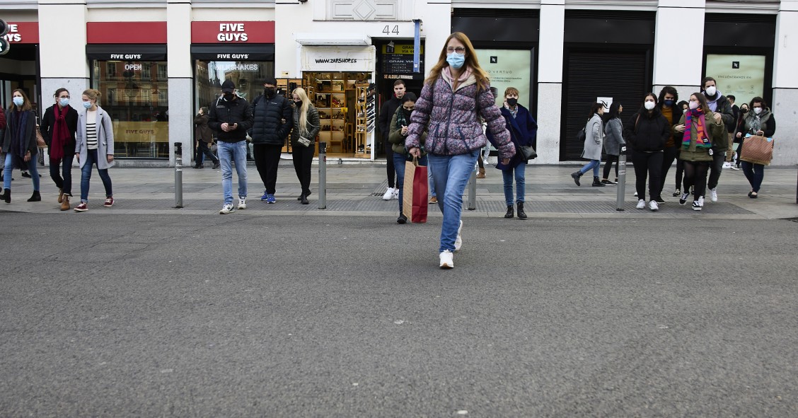 Archivo - Varias personas con bolsas pasean en una calle comercial del centro de Madrid.