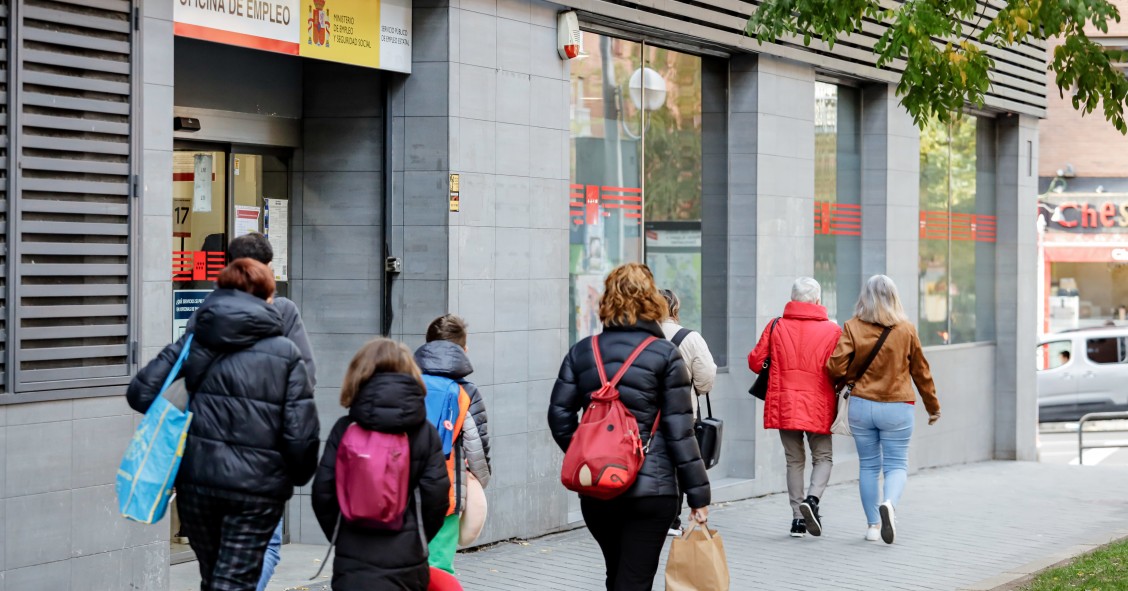 Archivo - Varias personas pasan frente a una oficina de empleo