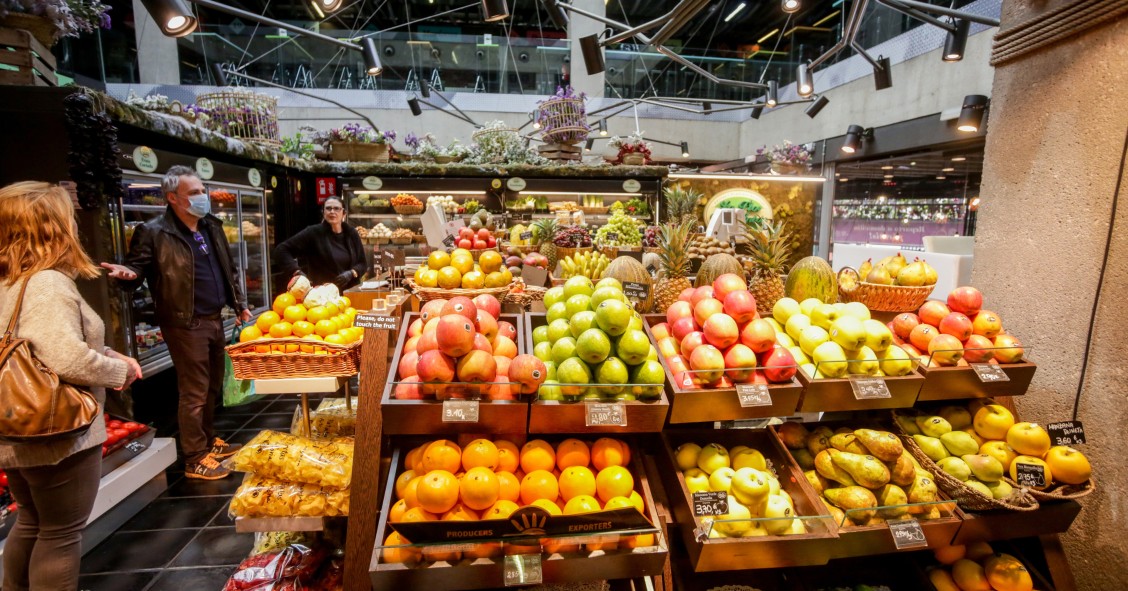 Archivo - Varios clientes hacen la compra en un puesto de fruta en el mercado de San Antón en Madrid (España)