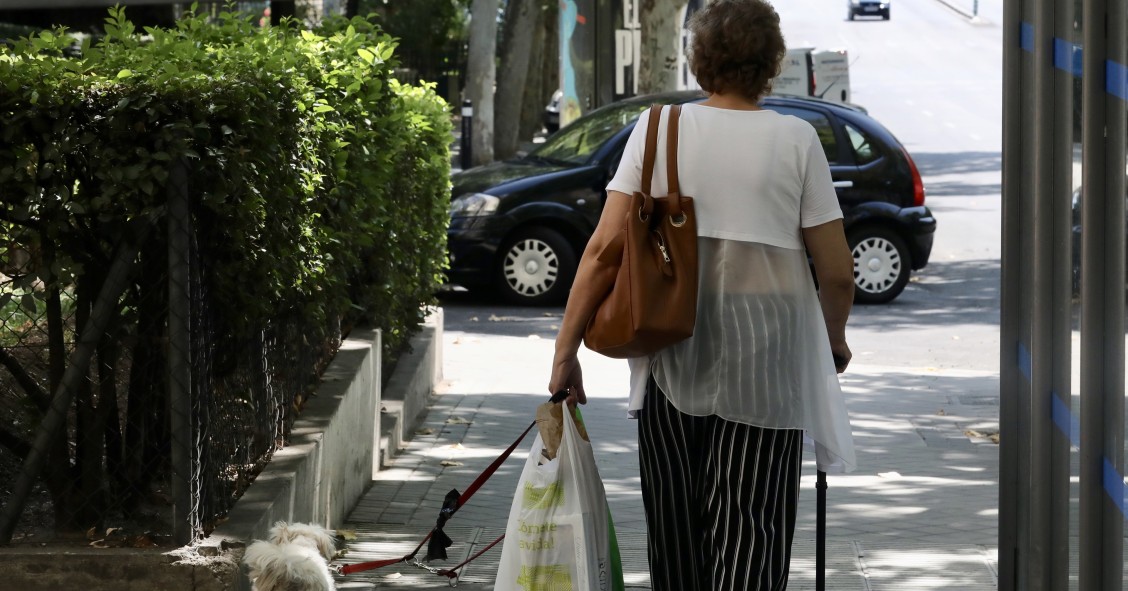 Archivo - Una mujer de la tercera edad pasea con su perro por una calle de Madrid (26 de julio de 2019). 