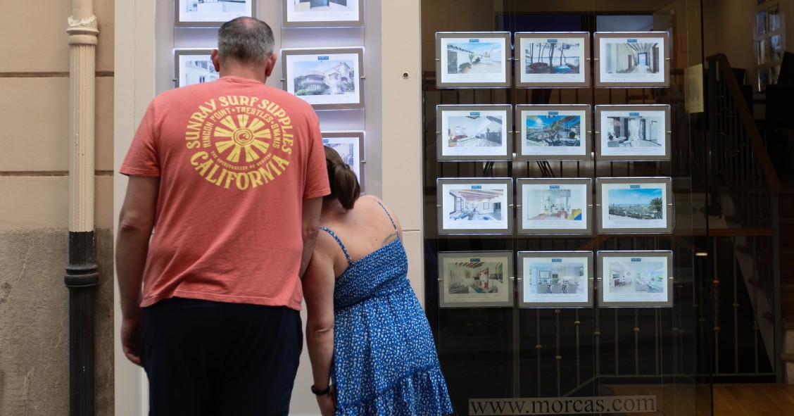 Archivo - Dos personas observan los anuncios de viviendas en venta en una inmobiliaria. 