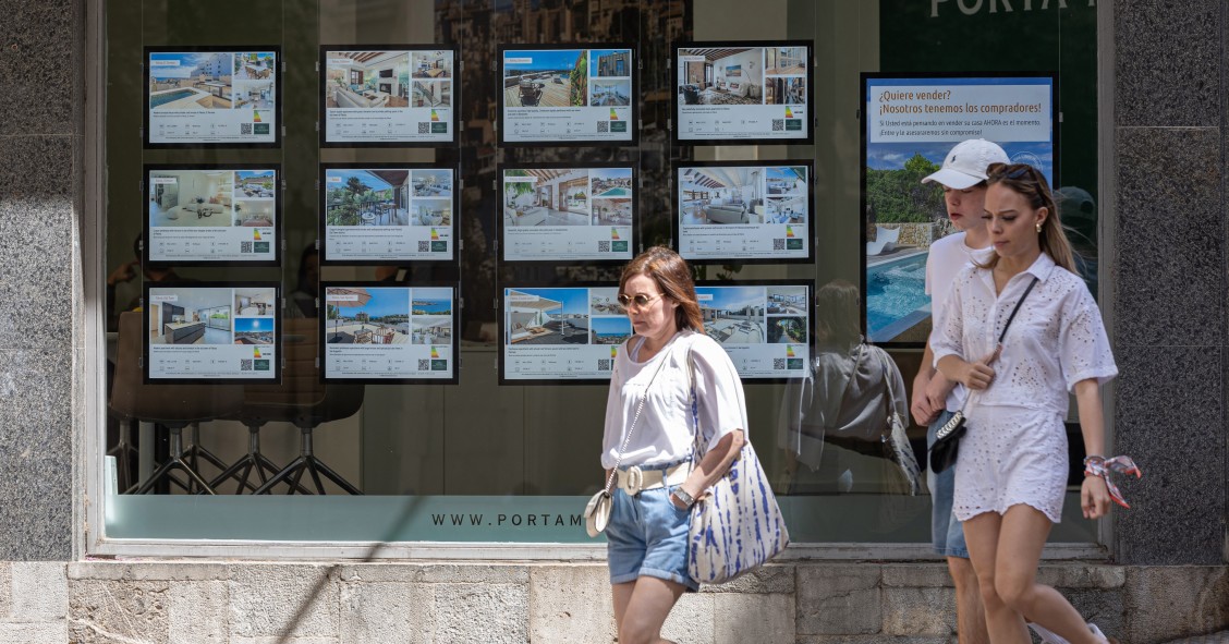 Archivo - Varias personas pasan junto a los anuncios de viviendas en venta en una inmobiliaria en Palma de Mallorca, Mallorca, Baleares (España).