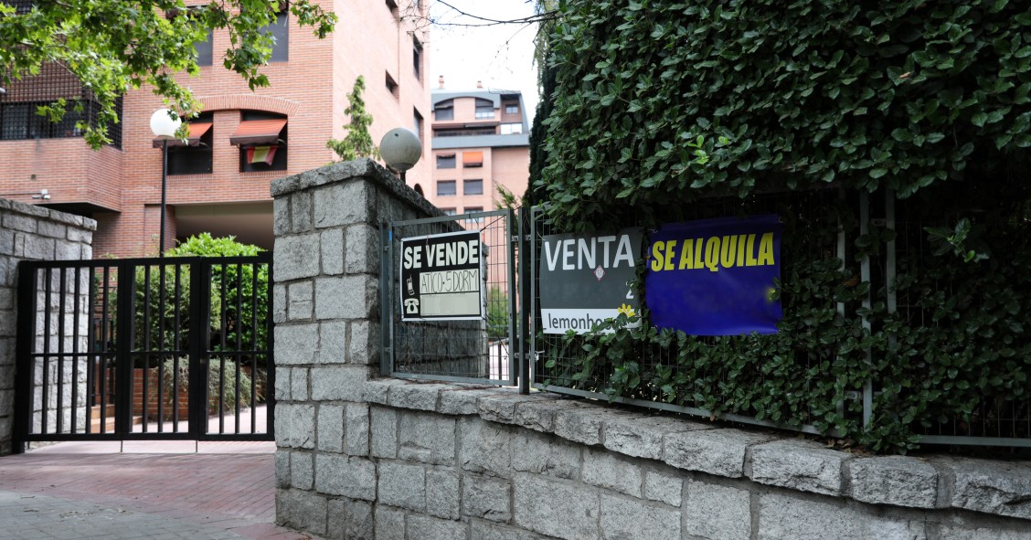 Archivo - En la valla de una urbanización, se ven colgados dos carteles de 'Se vende piso' y uno de 'Se alquila'.