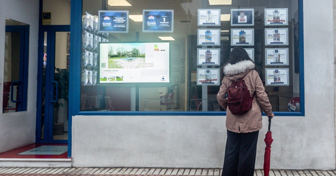 Archivo - Una mujer observa las ofertas de una inmobiliaria