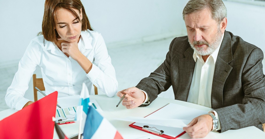 Dos hermanos firmando documentos relacionados con una herencia en una notaría