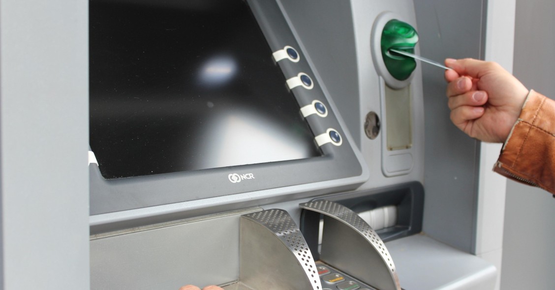 Persona introduciendo tarjeta en cajero automático para operar en cuenta bancaria compartida