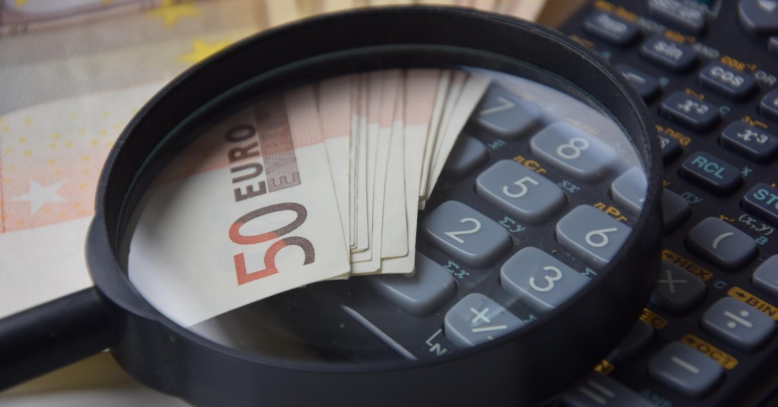 Lupa y calculadora junto a billetes de 50 euros sobre una mesa