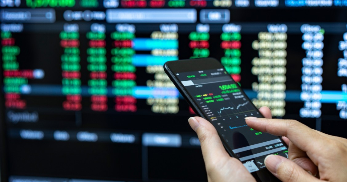 Archivo - Businessman checking stock market data. He using a mobile phone. Analysis economy data on forex earn graph.