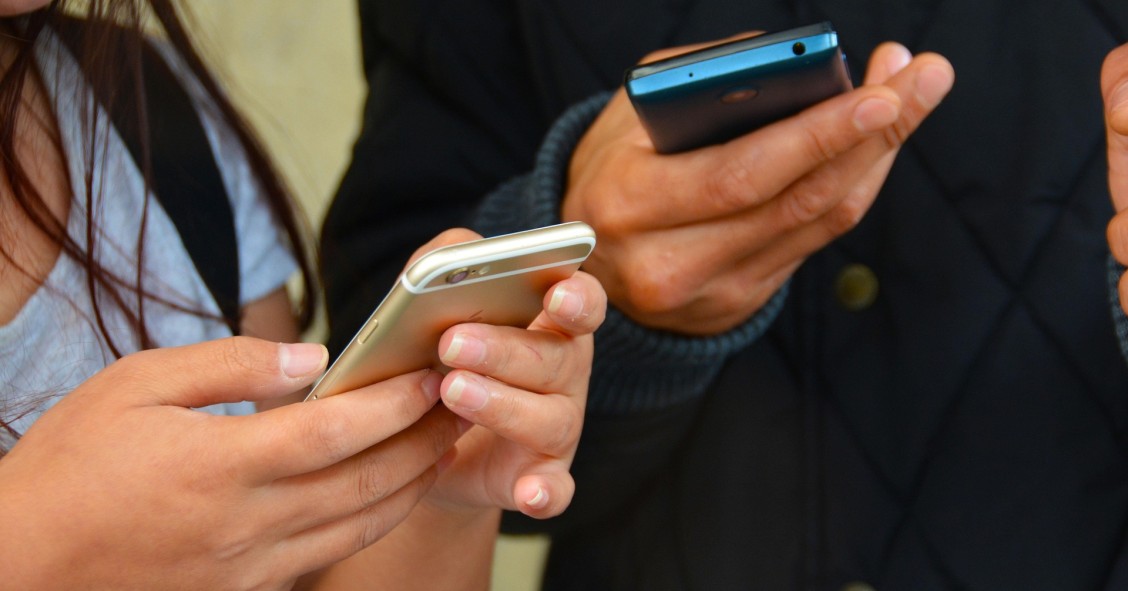 Dos personas consultando su móvil para evitar el phishing en vacaciones