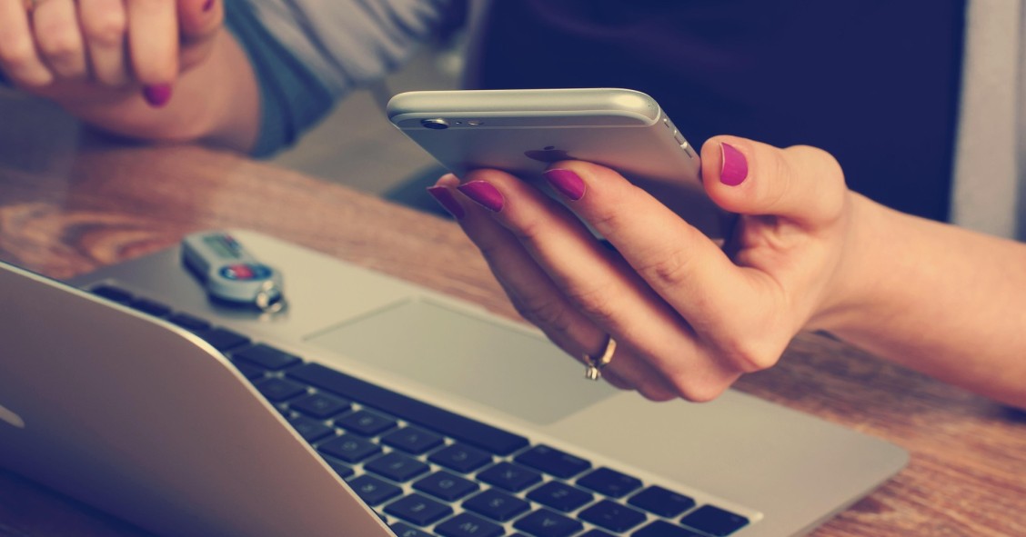 Víctima de phishing bancario revisando sus cuentas en el móvil y el portátil