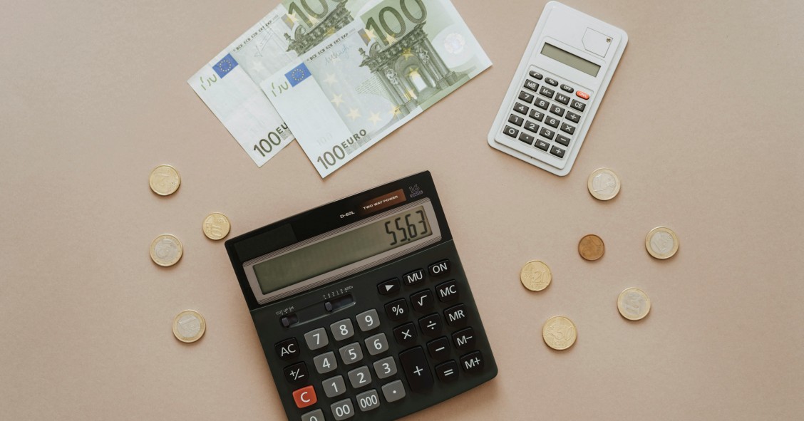 Dos calculadoras junto a billetes y monedas de euro representando el cálculo del IBI de una vivienda