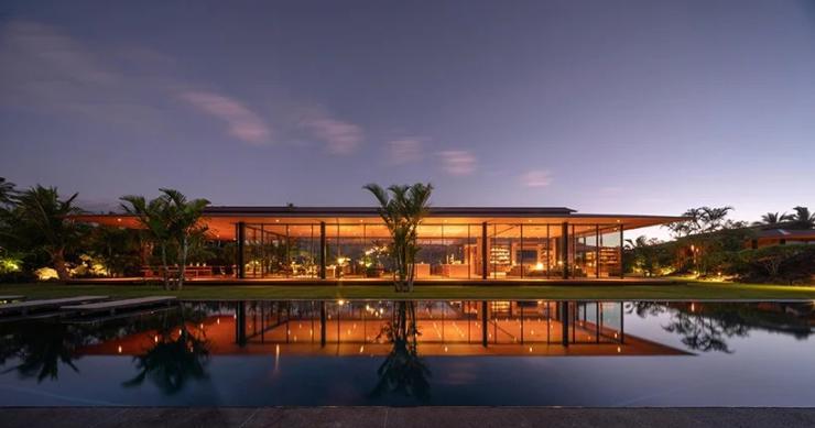 Una casa de lujo de madera y vidrio que parece flotar sobre la hierba en Hawai