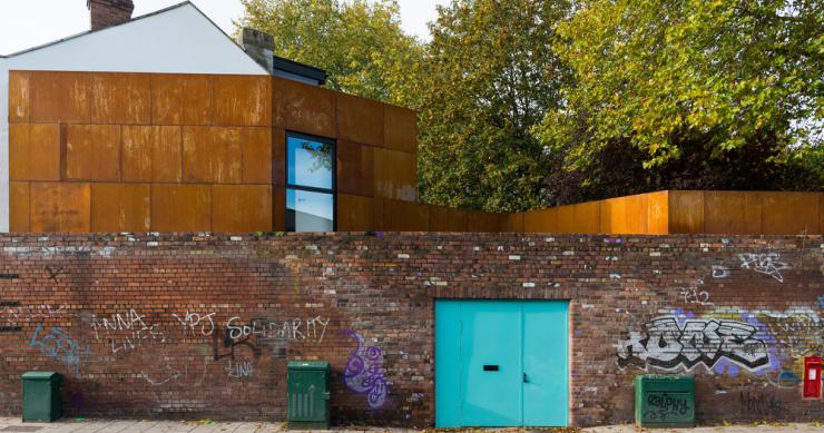 Una peculiar casa revestida con acero que se esconde tras un antiguo muro de ladrillo en Bristol
