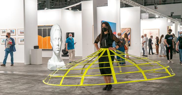 Artista realizando una performance con una escultura de Jaume Plensa al fondo