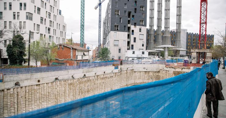 Un hombre mira una obra, en construcción, parada y sin trabajadores, por falta de suministros como el hormigón, en Vallecas