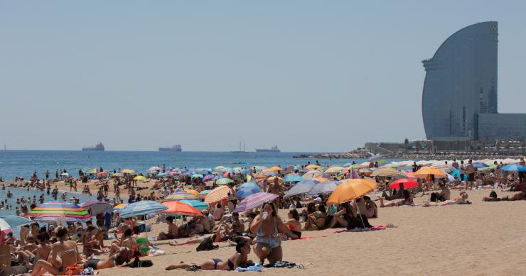 Varias personas se protegen del sol en la playa de la Barceloneta, en una imagen de archivo.