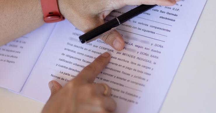Archivo - Una mujer con un bolígrafo, señala una escritura de compraventa de una hipoteca