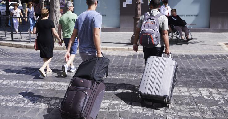  Dos turistas, con maletas, cruzan un paso de peatones a 21 de junio de 2022 en Sevilla (Andalucía, España)