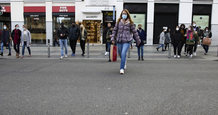 Archivo - Varias personas con bolsas pasean en una calle comercial del centro de Madrid.