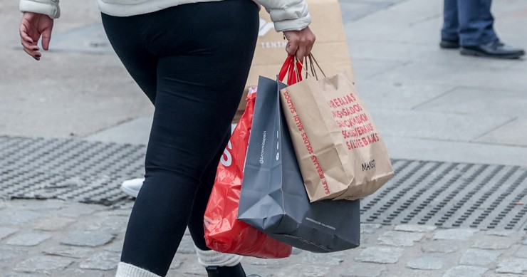 Archivo - Una persona camina con varias bolsas de compras en la calle comercial de Preciados, a 7 de enero de 2022, en Madrid