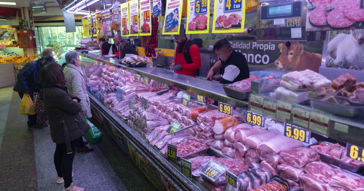 Varias personas compran en una carnicería en un mercado 