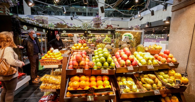 Archivo - Varios clientes hacen la compra en un puesto de fruta en el mercado de San Antón en Madrid (España)